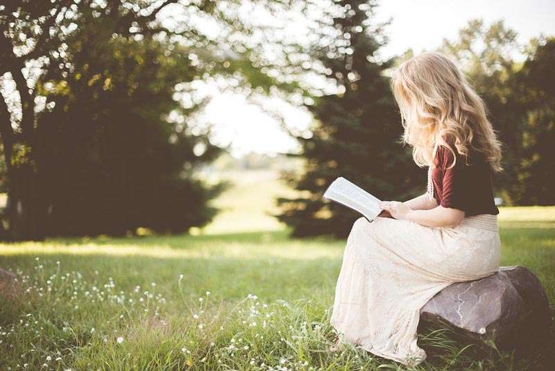 Niña leyendo un libro al aire libre