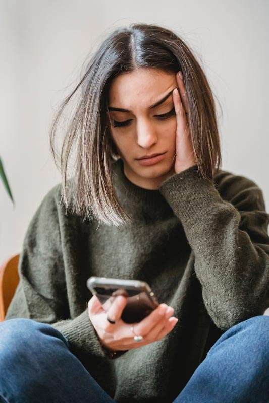 Mujer viendo dudosa el smartphone