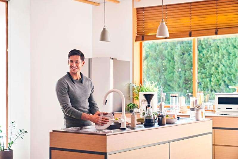 Hombre lavando trastes y usando bocina Sony neckband SRS-NB10