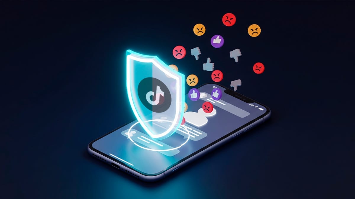 Imagen de un escudo, con el logo de TikTok, bloqueando emojis negativos, abajo un teléfono movil, haciendo referencia a que puedes bloquear a personas