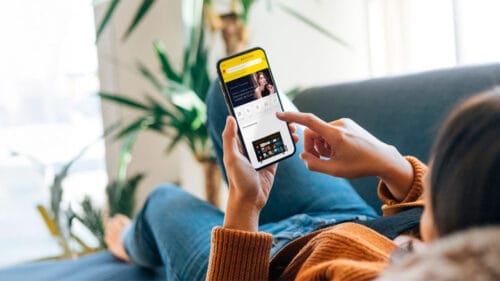 Mujer viendo su teléfono móvil, revisando la página de Unboxing Days de Mercado libre en busca de las mejores ofertas. Fuente: MercadoLibre